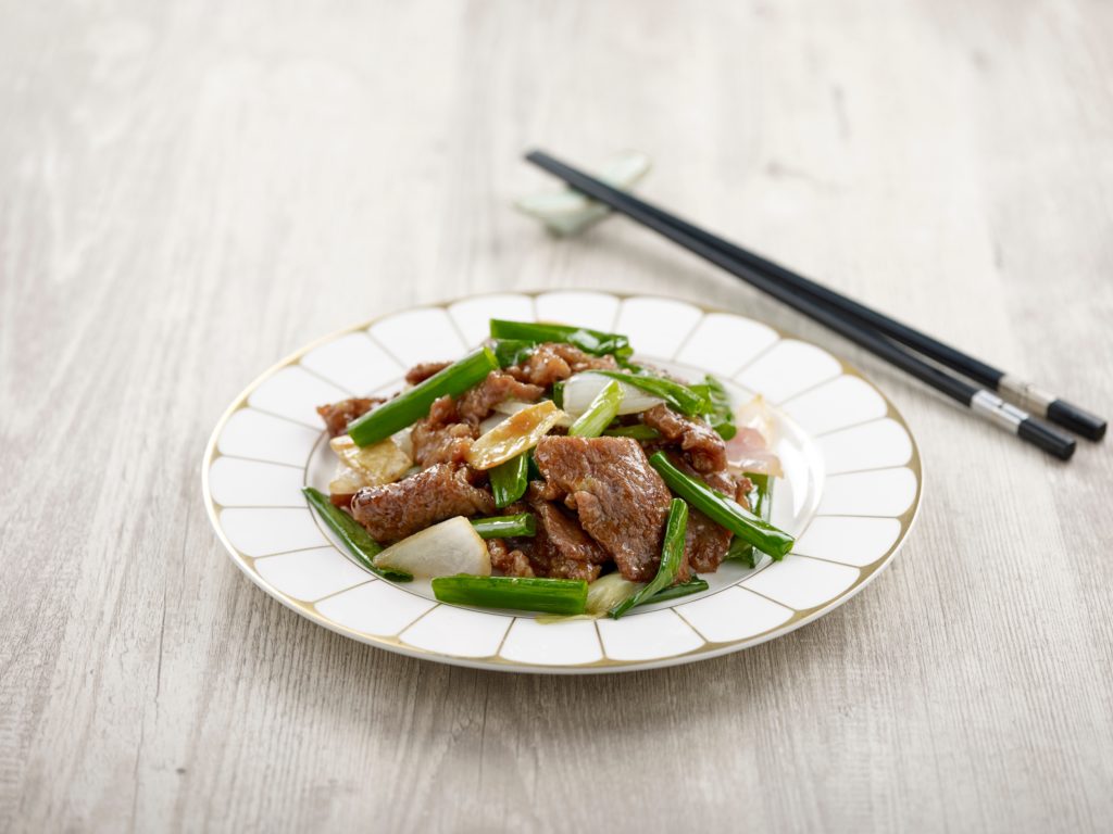 Stir-fried Sliced US Marbled Beef with Ginger and Spring Onion with chopsticks served in a dish isolated on mat side view on grey background